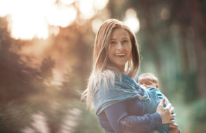 Mother carrying her baby in cloth baby carrier