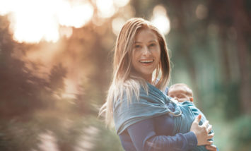 Mother carrying her baby in cloth baby carrier