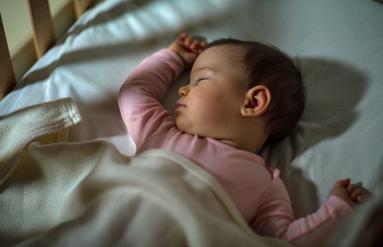 A baby sleeping in a cot