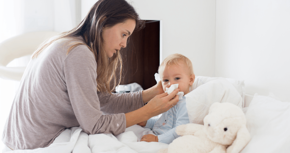 A mum wiping a babys' runny nose