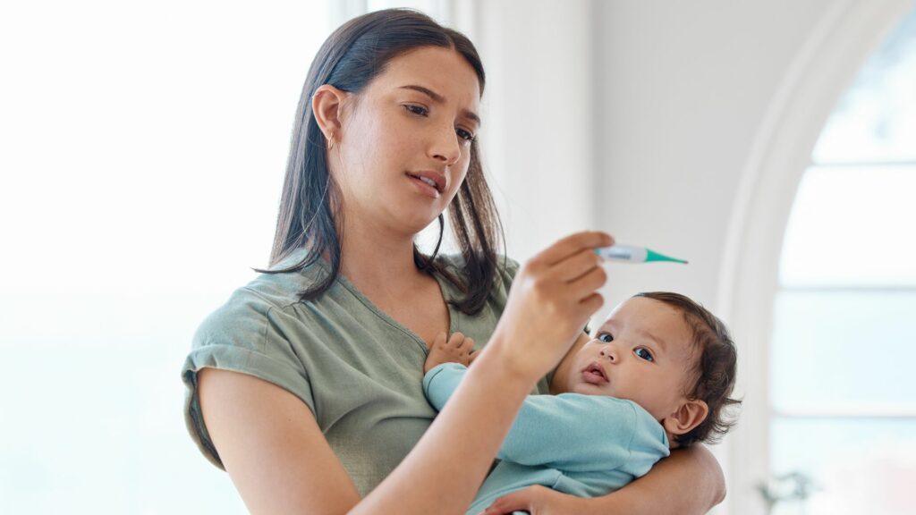 A mum holding a baby after taking it's temperature